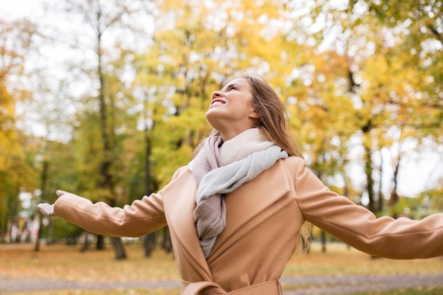 concepto de temporada y gente - hermosa mujer joven feliz caminando en el parque de otoño