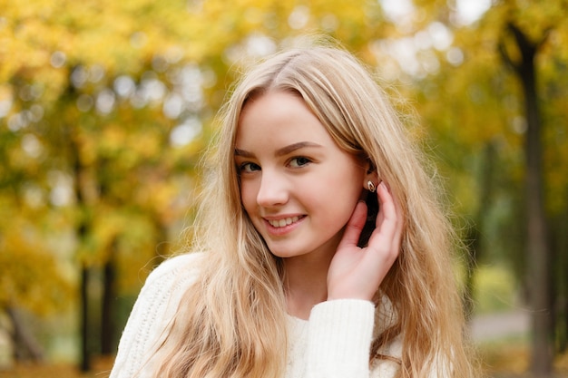 Concepto de temporada y personas - hermosa mujer joven feliz divirtiéndose con hojas en el parque de otoño