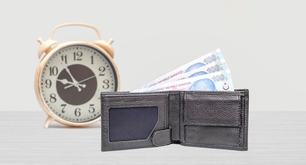 Concepto de tiempo y dinero Reloj y 100 liras turcas sobre la mesa