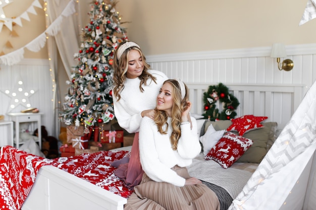 Concepto de tiro de Navidad, dos niñas sonrientes felices, hermana de amigos en el dormitorio junto al árbol