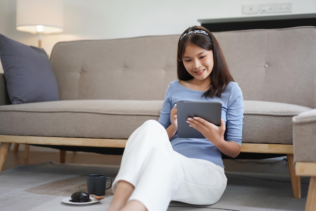 Concepto de trabajo desde casa Las mujeres de negocios se sientan en el suelo en la sala de estar y escriben datos en la tableta