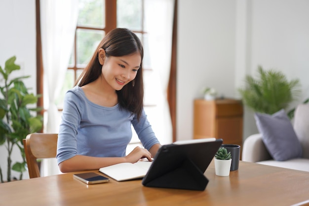 Concepto de trabajo desde casa Mujeres de negocios tomando notas mientras lee datos en la tableta en la sala de estar