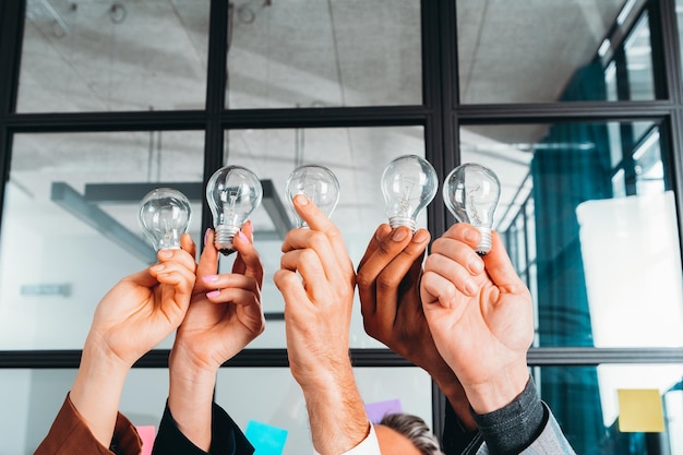 Concepto de trabajo en equipo y lluvia de ideas con empresarios que comparten una idea con una lámpara