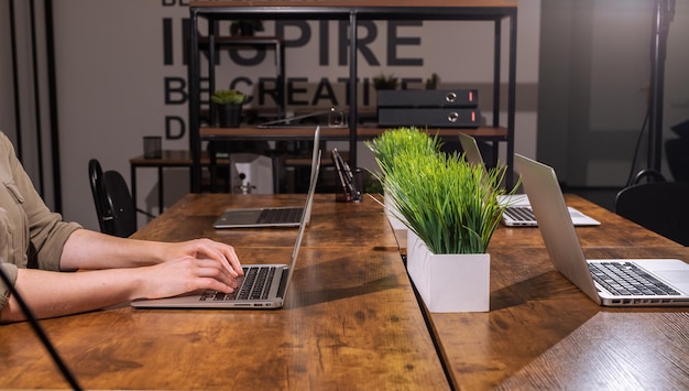 Concepto de trabajo nocturno Mano portátil en el escritorio de la oficina por la noche Trabajando solo en un interior moderno