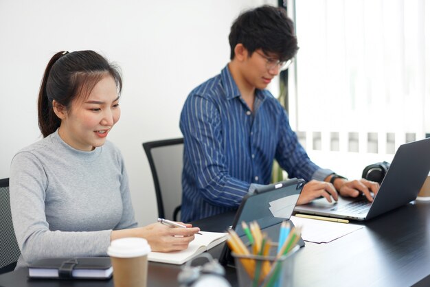 Concepto de trabajo de oficina dos personas de negocios que trabajan en los dispositivos con dos tazas de café en la oficina.