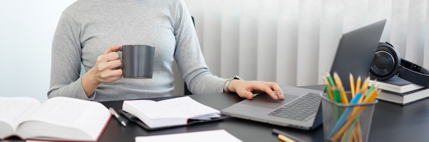 Concepto de trabajo de oficina una secretaria sosteniendo una taza de café relajadamente haciendo su trabajo.