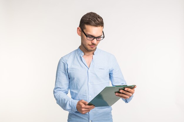 Foto concepto de trabajo y personas - apuesto joven con gafas mirando notas sobre la pared blanca.