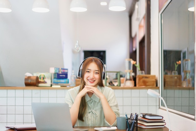 Concepto de trabajo remoto Mujer empresaria usa auriculares para escuchar música en el espacio de coworking