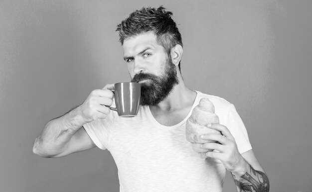 Concepto de tradición matutina Pero primero café Disfruta cada sorbo de café Combinación perfecta El hombre comienza la mañana con una taza de café y croissant recién hecho Hipster barbudo disfruta del desayuno bebe café