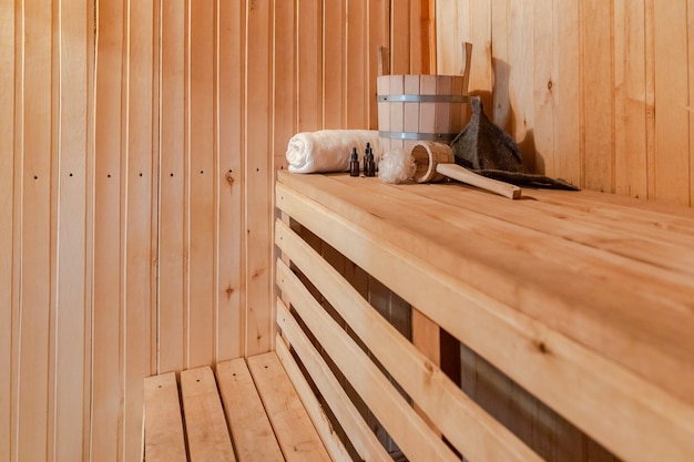 Concepto tradicional del balneario ruso antiguo de la casa de baños. Detalles del interior Sauna finlandesa de vapor con accesorios de sauna tradicionales, conjunto de palangana, toalla, aceite aromático, cuchara de fieltro. Relajarse concepto de baño de pueblo de campo.