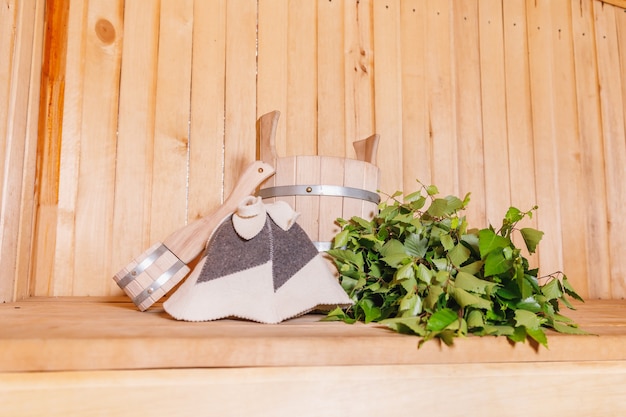 Concepto tradicional del balneario ruso antiguo de la casa de baños. Detalles del interior Sauna finlandesa de vapor con accesorios tradicionales de sauna cuenca de fieltro de escoba de abedul. Relajarse concepto de baño de pueblo de campo.