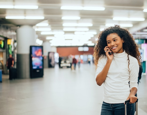 Concepto del transporte aéreo con la mujer de negocios casual joven que habla en el teléfono.