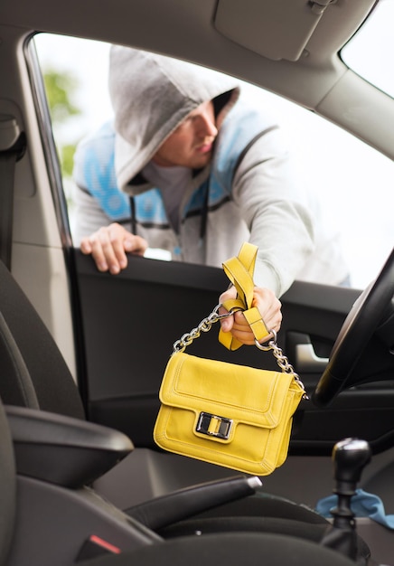 Concepto de transporte, delincuencia y propiedad: ladrón robando la bolsa del coche