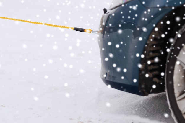 concepto de transporte, invierno y vehículo - cierre de coche remolcado con cuerda de remolque