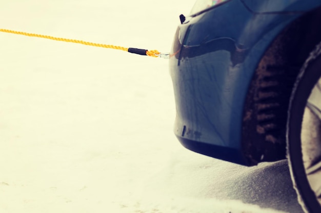 concepto de transporte, invierno y vehículo - cierre de coche remolcado con cuerda de remolque