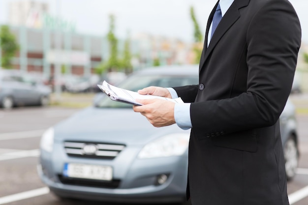 concepto de transporte y propiedad - hombre con documentos de coche fuera