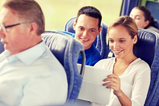 concepto de transporte, turismo, viaje por carretera, tecnología y personas - pareja feliz con tableta en el autobús de viaje