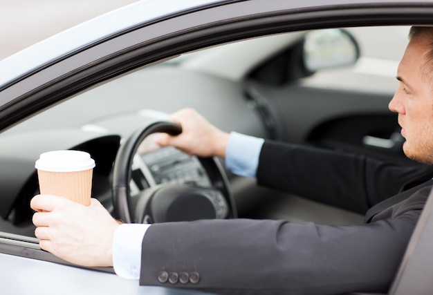 Concepto de transporte y vehículo: hombre tomando café mientras conduce el automóvil