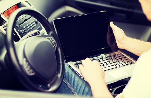 concepto de transporte y vehículo - hombre usando una computadora portátil en el auto