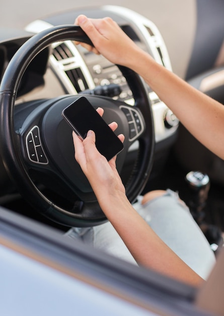 Concepto de transporte y vehículo: mujer que usa el teléfono mientras conduce el automóvil