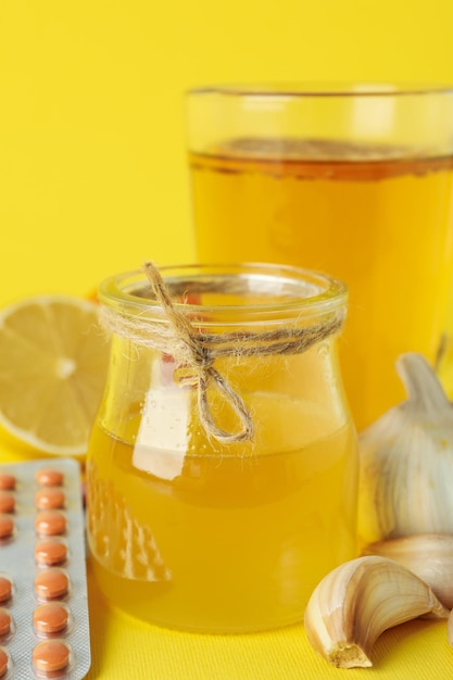 Concepto de tratamiento de resfriados con miel y ajo sobre fondo amarillo