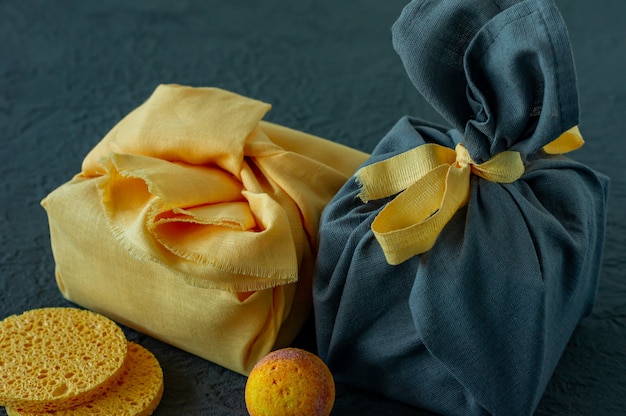 Concepto de tratamiento de spa y cuidado corporal en los colores del año 2021 - Amarillo iluminado y gris definitivo. Regalo envuelto en estilo Furoshiki.