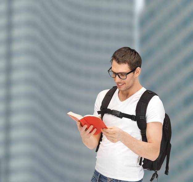 concepto de turismo, educación y vacaciones - estudiante viajero con anteojos con mochila y libro