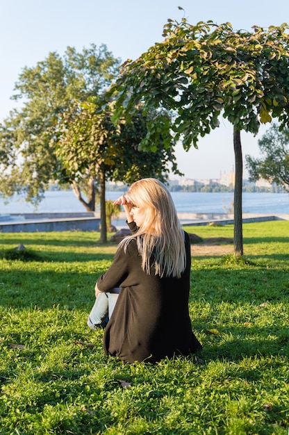 Concepto de turismo y recreación. Mujer mirando a lo lejos mientras está sentado en el césped