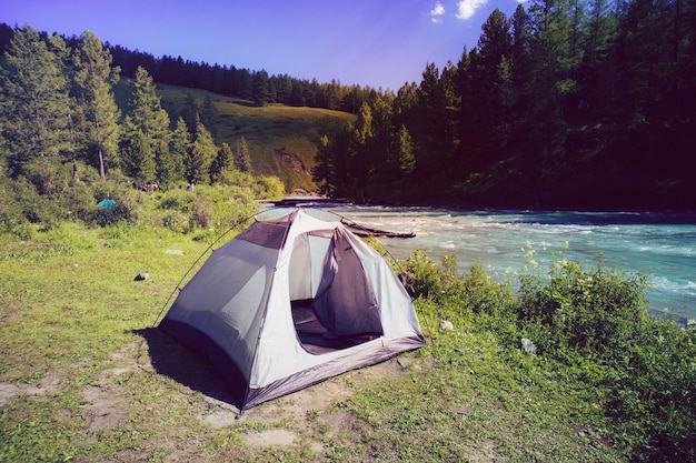 Concepto de turismo y viajes Hermoso paisaje de verano con montañas y carpa turística Puestos amarillos cerca del lago en las montañas Día soleado brillante en las montañas