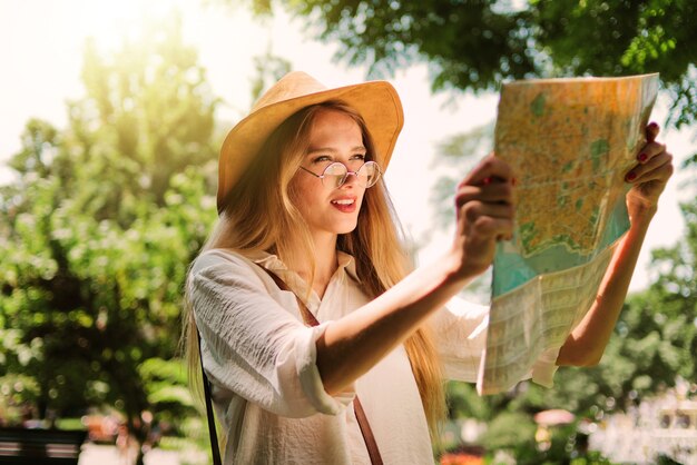 Concepto de turismo, viajes a nuevas ciudades. Una joven con sombrero de fieltro disfruta de un mapa de la ciudad.