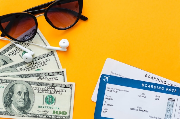 concepto de turismo, viajes y objetos - billete de avión, dinero, sobre fondo de hormigón amarillo
