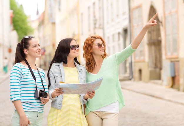 concepto de turismo, viajes, ocio, vacaciones y amistad - adolescentes sonrientes con mapa y cámara al aire libre