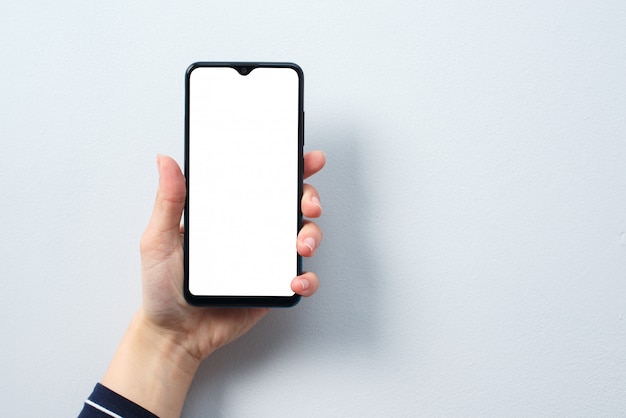 Concepto de uso del teléfono inteligente. Smartphone con una pantalla en blanco blanca en la mano de una mujer.