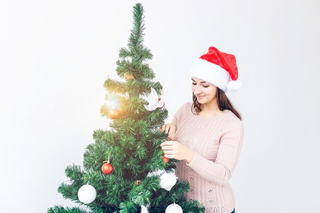 Concepto de vacaciones - Chica con sombrero de santa decorado árbol de Navidad. Esperando la Navidad.