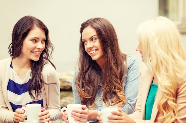 concepto de vacaciones, comida y turismo - tres hermosas chicas tomando café en la cafetería