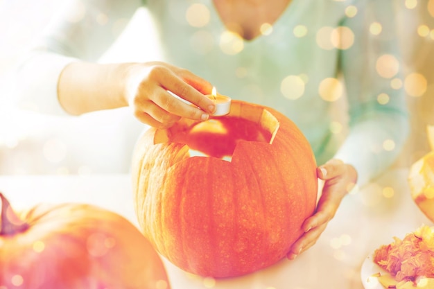 Concepto de vacaciones, halloween, decoración y personas - cerca de mujer con calabazas en casa