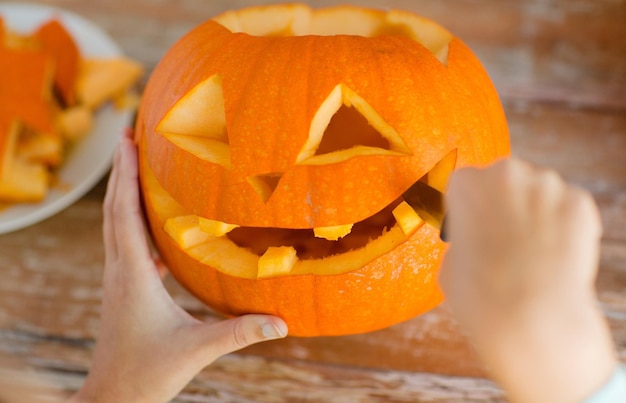 Concepto de vacaciones, halloween, decoración y personas - cerca de mujer con calabazas en casa