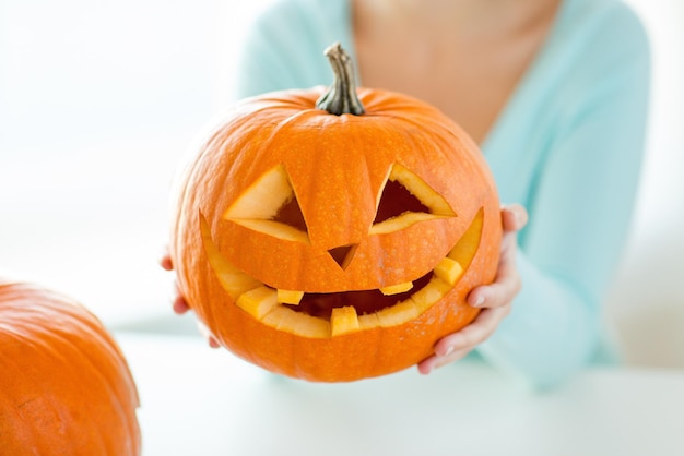 Concepto de vacaciones, halloween, decoración y personas - cerca de mujer con calabazas en casa