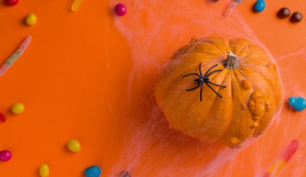 Concepto de vacaciones de Halloween. Sobre fondo naranja, calabaza y dulces. Vista desde arriba. Copia espacio