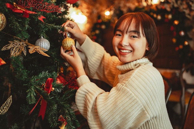 Concepto de vacaciones de invierno, mujer feliz decorando el árbol de Navidad para la celebración del año nuevo.