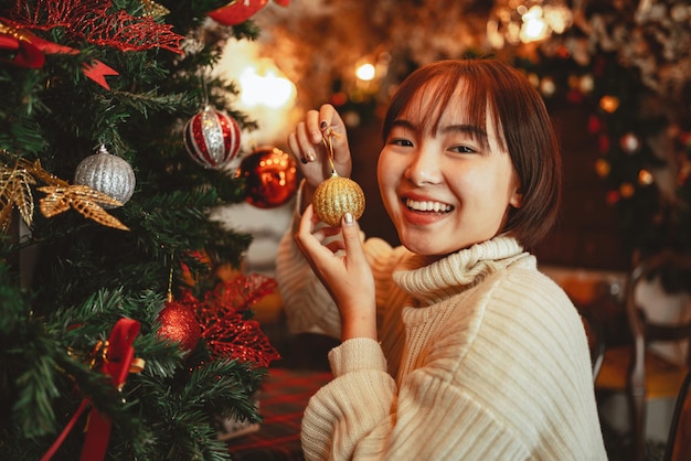 Concepto de vacaciones de invierno, mujer feliz decorando el árbol de Navidad para la celebración del año nuevo.