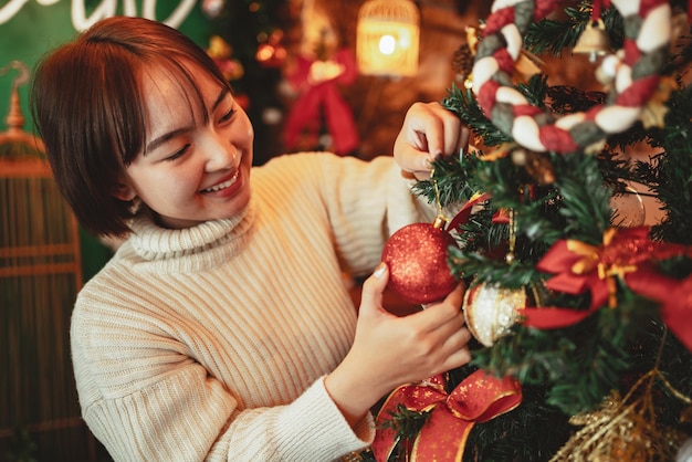 Concepto de vacaciones de invierno, mujer feliz decorando el árbol de Navidad para la celebración del año nuevo.