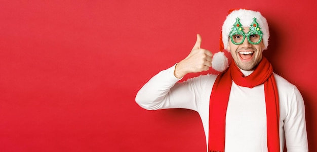 Concepto de vacaciones de invierno de Navidad y celebración chico alegre con sombrero de santa y gafas de fiesta sho ...