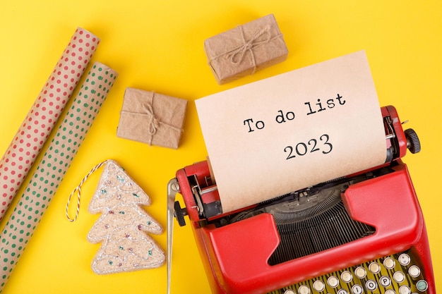 Foto concepto de vacaciones máquina de escribir roja con texto lista de tareas 2023 cajas de regalo y papel de regalo