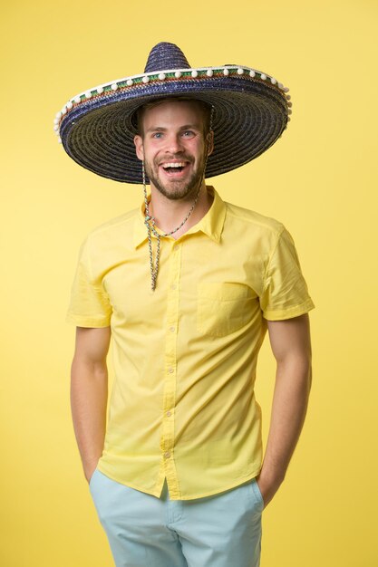 Foto concepto de vacaciones mexicanas hombre cara alegre estado de ánimo festivo posando en sombrero sombrero fondo amarillo chico con cerdas se ve festivo en sombrero hombre celebrar fiesta tradicional nacional mexicana