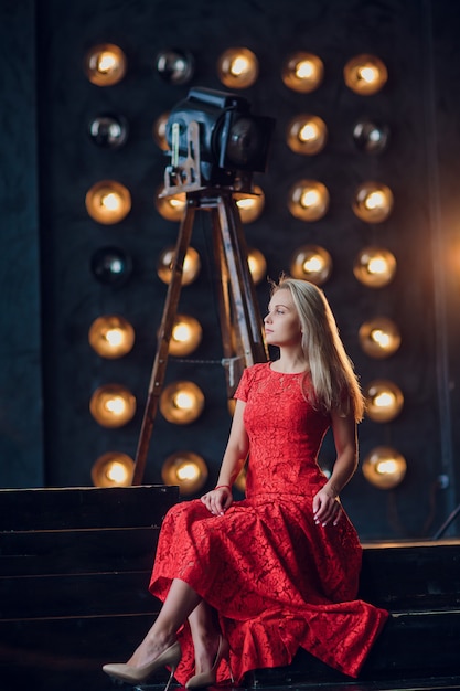 Concepto de vacaciones y moda - hermosa mujer sexy en vestido rojo sobre fondo de luces