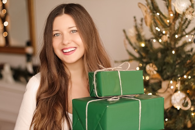 Concepto de vacaciones de Navidad y regalos sostenibles mujer sonriente feliz sosteniendo regalos envueltos con ec ...