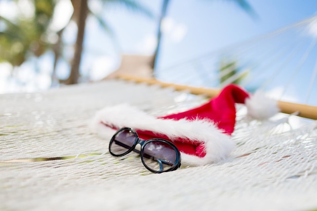 concepto de vacaciones, navidad y vacaciones - imagen de hamaca con sombrero de ayudante de santa y gafas de sol
