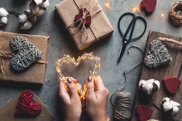 Concepto de vacaciones, personas y celebración - cerca de mujer decorando regalos de San Valentín