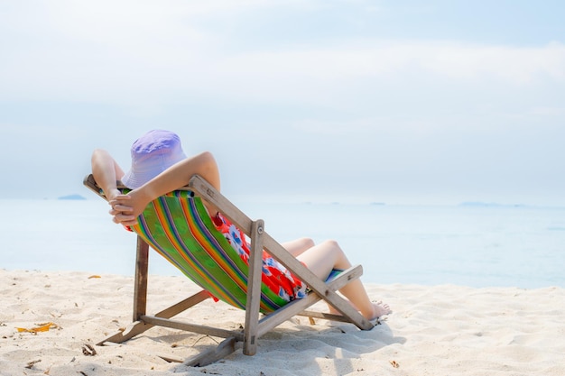 Concepto de vacaciones en la playa de verano Mujer de Asia con sombrero relajante y brazo arriba en la playa de sillas en Tailandia